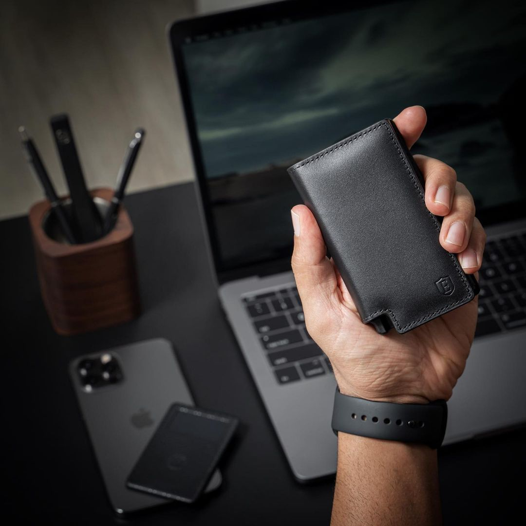 man holding up ekster wallet in front of laptop